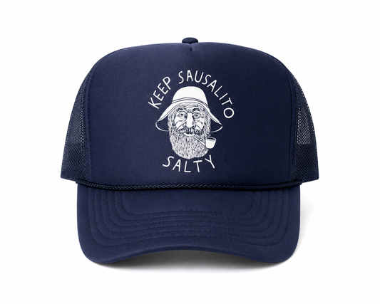 A navy blue trucker hat with a white graphic of a bearded man wearing a hat and smoking a pipe, surrounded by the text 'KEEP SAUSALITO SALTY'